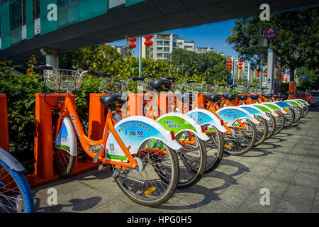 SHENZEN, CHINA - 29 JANUARY, 2017: City bike parking, row of orange bikes connected to automatic machines on city street. Stock Photo