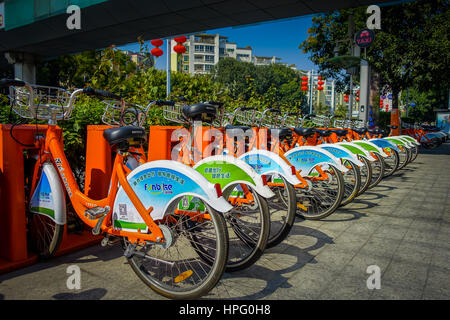 SHENZEN, CHINA - 29 JANUARY, 2017: City bike parking, row of orange bikes connected to automatic machines on city street. Stock Photo