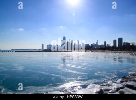 Sun Setting over Chicago's Lake Michigan Lakefront in January 2017 Frigid Winter scene with skyline or cityscape and frozen lake water Stock Photo