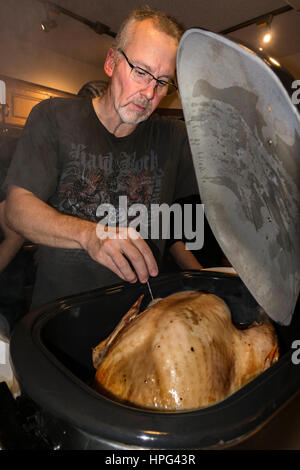 Hard working husband checking temperature of Thanksgiving turkey in the roaster. Champlin Minnesota MN USA Stock Photo