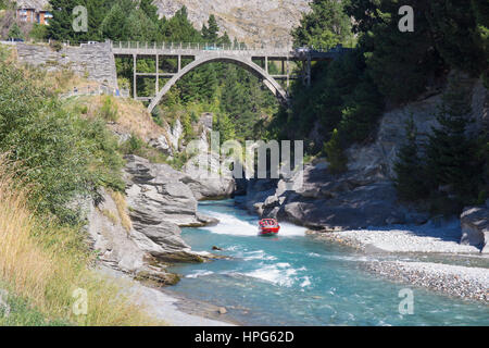 Queenstown, Otago, New Zealand. Shotover Jet boat passing beneath the Edith Cavell Bridge over the Shotover River. Stock Photo