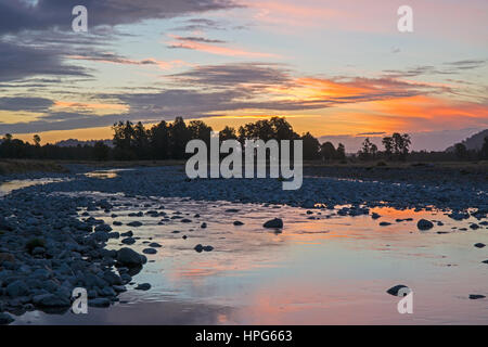 Fox Glacier, Westland Tai Poutini National Park, West Coast, New Zealand. Colourful sky reflected in a tributary of the Fox River at sunset. Stock Photo
