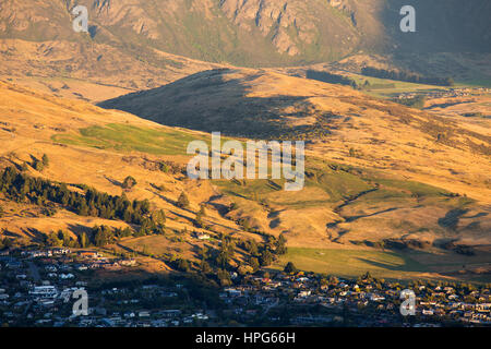 Queenstown, Otago, New Zealand. View to the lower slopes of the Remarkables and the exclusive suburb of Kelvin Heights, sunset. Stock Photo