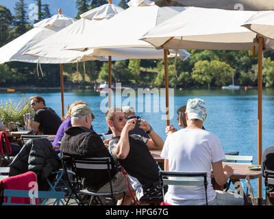 Queenstown, Otago, New Zealand. Customers on the terrace of a lakefront café, Queenstown Bay. Stock Photo
