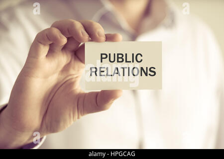 Closeup on businessman holding a card with text PUBLIC RELATIONS, business concept image with soft focus background and vintage tone Stock Photo