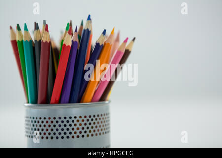 Colored pencils kept in pencil holder on white background Stock Photo