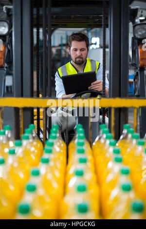 Attentive factory worker using digital tablet in forklift Stock Photo