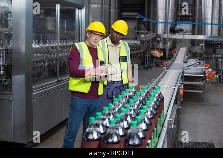 Two factory workers monitoring cold drink bottles at drinks production plant Stock Photo