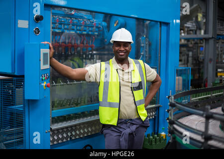 Smiling factory worker standing near machine control cabinet in factory Stock Photo