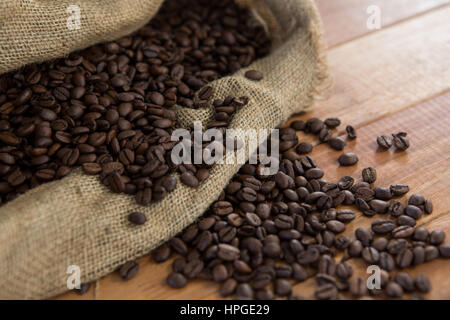 Roasted coffee beans in sack bag on wooden background Stock Photo