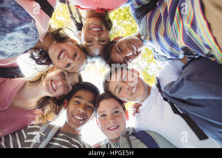 Portrait of smiling school kids forming a huddle in campus at school Stock Photo