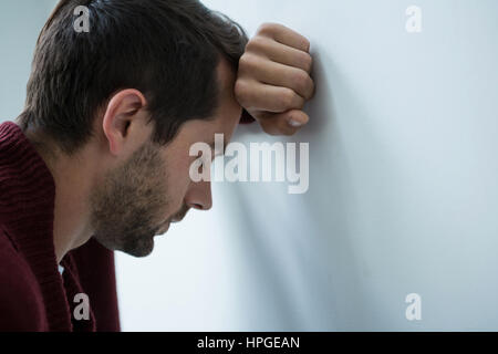 Close-up of a stressed man leaning on wall Stock Photo
