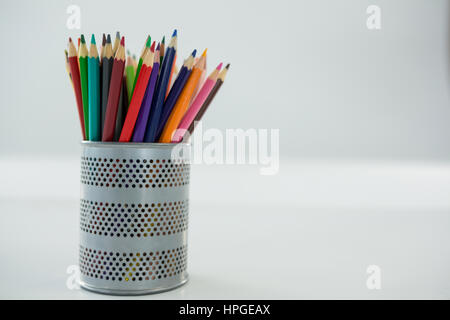Colored pencils kept in pencil holder on white background Stock Photo