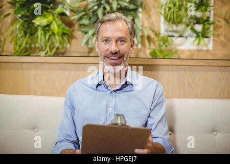 Portrait of smiling doctor holding clipboard in clinic Stock Photo