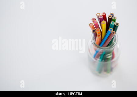 Colored pencils kept in jar on white background Stock Photo