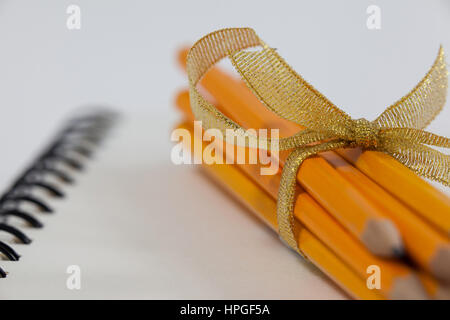Bunch of pencils wrapped with ribbons on book Stock Photo