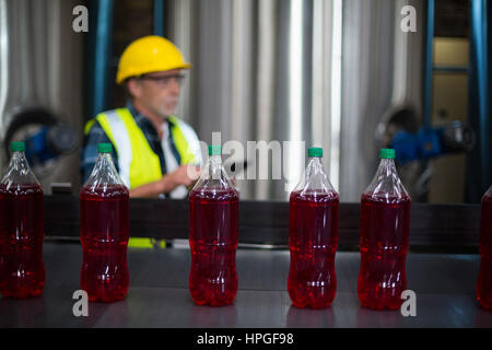 Male factory worker monitoring cold drink bottles at drinks production factory Stock Photo