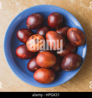 Easter eggs in the blue ceramic bowl. Painted brown with spots and cracks. Stock Photo
