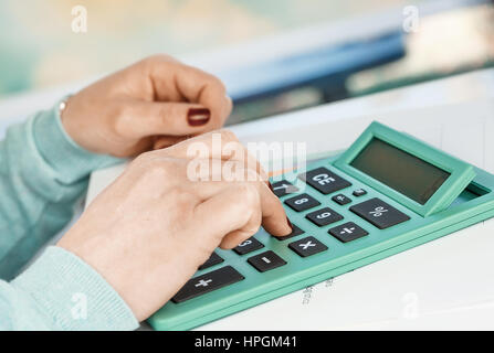 Close-up portrait of red nails businesswoman hand while using calculator. Stock Photo