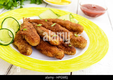 Deep frying small fish capelin on a plate on white wooden background. Close up Stock Photo