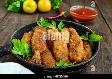 Deep frying small fish capelin in a pan on a dark wooden background. Good snack to beer. Stock Photo