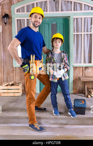 father and son in helmets with building tools Stock Photo