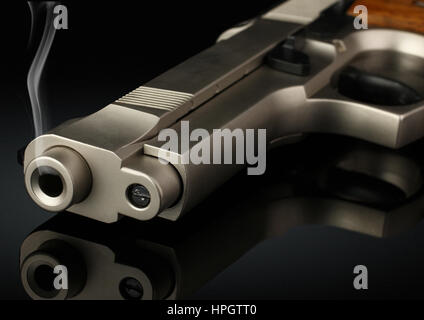 Closeup of handgun with smoke barrel on black, soft focus Stock Photo