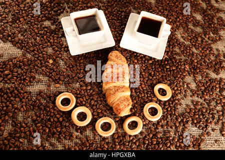 Funny smiley of coffee beans with white cups and croissant Stock Photo