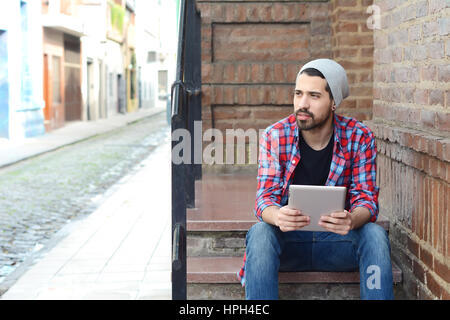 Young latin man touching at tablet at the street. Stock Photo
