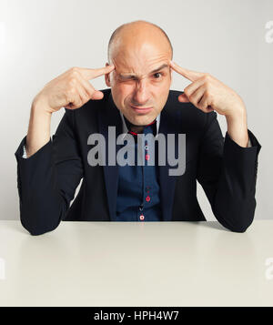 funny bald businessman trying to think seriously. Man Sitting at desk Stock Photo