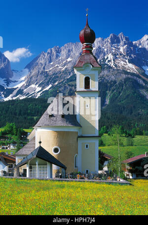 Spring flowers at Going with its onion domed church, Wilder Kaiser mountains in background, Tyrol, Austria. Stock Photo