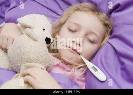 Krankes Maedchen liegt mit Fieberthermometer im Bett - sick girl with clinical thermometer in bed, Model released