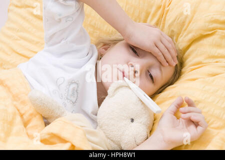 Krankes Maedchen liegt mit Fieberthermometer im Bett - sick girl with clinical thermometer in bed, Model released