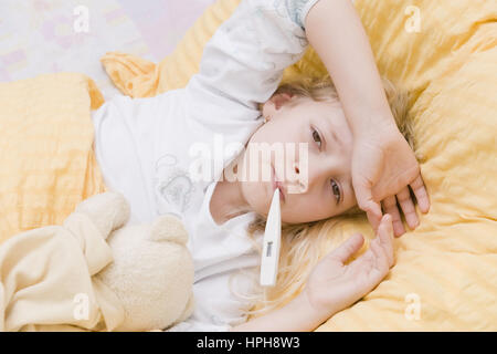 Krankes Maedchen liegt mit Fieberthermometer im Bett - sick girl with clinical thermometer in bed, Model released