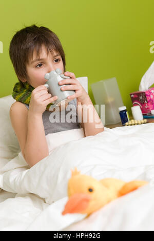 Kranker Junge mit Tasse Tee im Bett - sick boy with cup of tea in bed, Model released Stock Photo