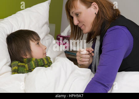 Mutter sitzt am Bett von krankem Sohn - sick son in bed, Model released