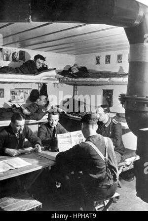 The Nazi propaganda image shows German Wehrmacht soldiers in the common room in a bunker on the Atlantic Wall. Published in February 1944. A Nazi reporter has written on the reverse of the image on 17.02.1944, 'In a grenadiers' station on the Atlantic Wall. Leisure hours in the common room of the grenadiers. In the foreground, part of a modern ventilation system. On the ceiling, the grain of the concrete bunker is clearly visible.' Fotoarchiv für Zeitgeschichte - NO WIRE SERVICE -  | usage worldwide Stock Photo