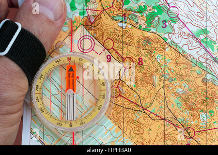 Hand holding a compass on an orienteering map Stock Photo