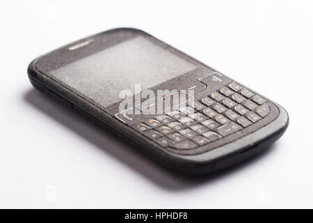 Side view close up of old black smartphone mobile with qwerty keyboard covered in dust and isolated on white background Stock Photo