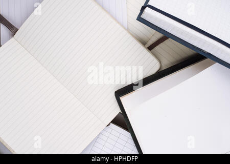 horizontal top view of many open notebooks in different shapes and sizes with white pages Stock Photo
