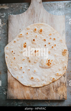 Homemade whole wheat flour tortilla on wooden board, on metal table Stock Photo