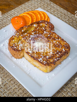 French toast made from homemade bread on a square white plate with a pat of butter Stock Photo