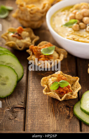 Homemade hummus in tortilla bowls with dried peppers, small appetizers Stock Photo