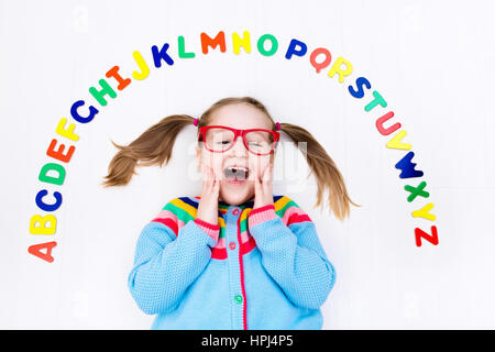 Happy preschool child learning to read and write playing with colorful roman alphabet letters. Educational abc toys and books for kids. School student Stock Photo