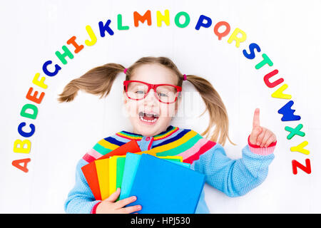 Happy preschool child learning to read and write playing with colorful roman alphabet letters. Educational abc toys and books for kids. School student Stock Photo