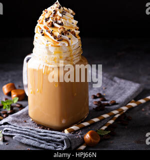 Caramel iced latte with whipped cream and syrup on dark background Stock Photo