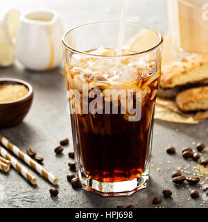 Iced coffee being poured in a tall glass with ice Stock Photo