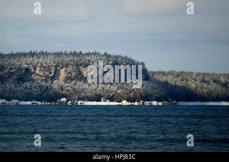 Snow covered trees on a limestone cliff on the Bruce Peninsula. Ontario.  Isthmus Bay near Lions head. Stock Photo