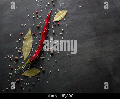 Red pepper pungent spices and bay leaf on the black tree. View from above. Space for text. Stock Photo