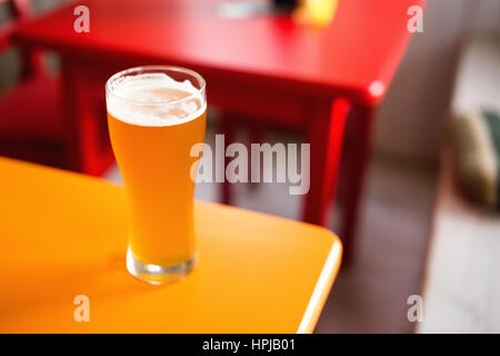 Glass of craft beer pale ale APA on colorful table in hipster bar. Shallow depth of field. Top angled view Stock Photo